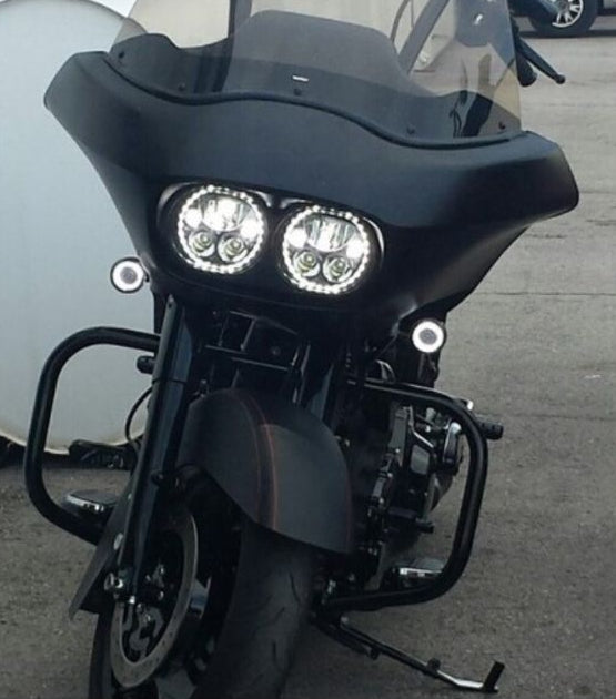 Close-up of a motorcycle's front headlight and fender on a road.